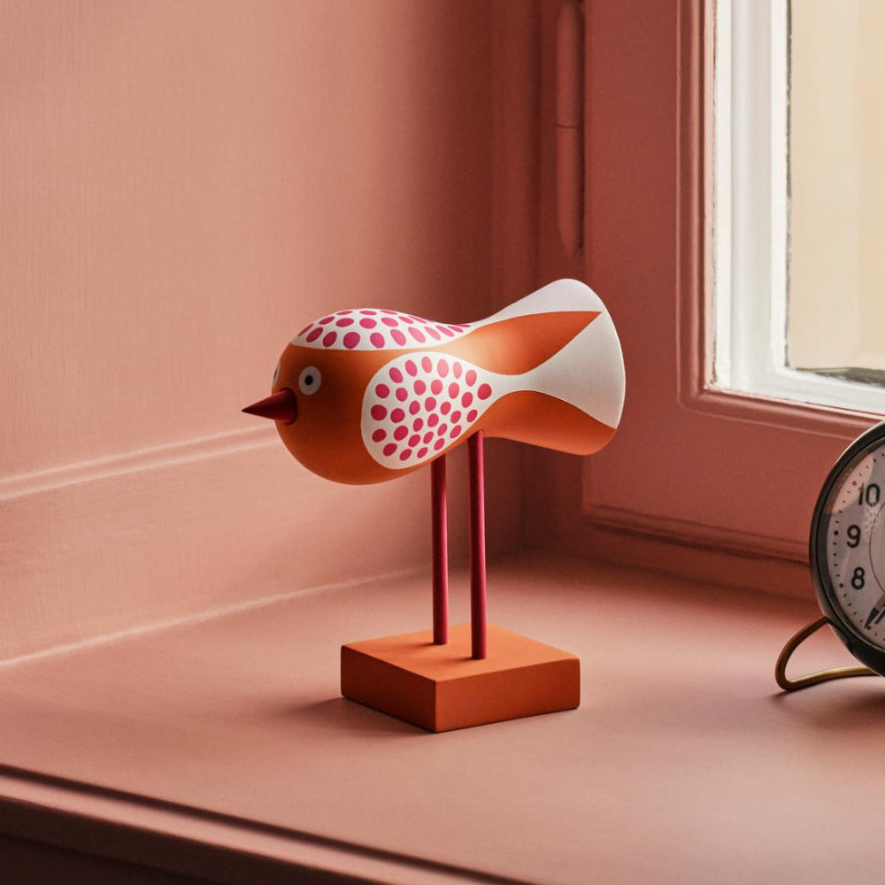 Decorative items on a windowsill including a fish-shaped lamp, clock, and vase with flowers.