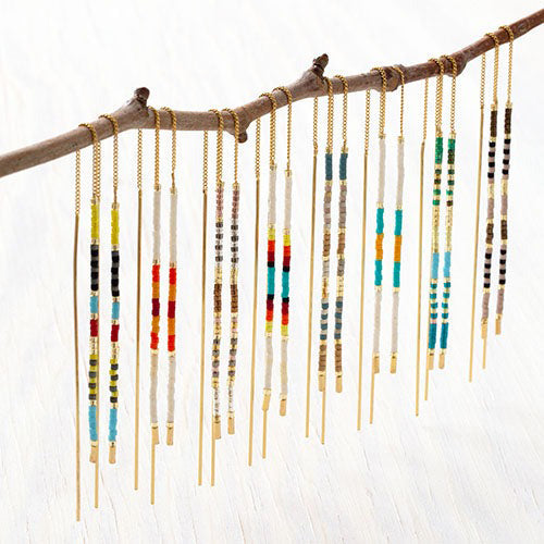 Different colored threader earrings hanging on branch.