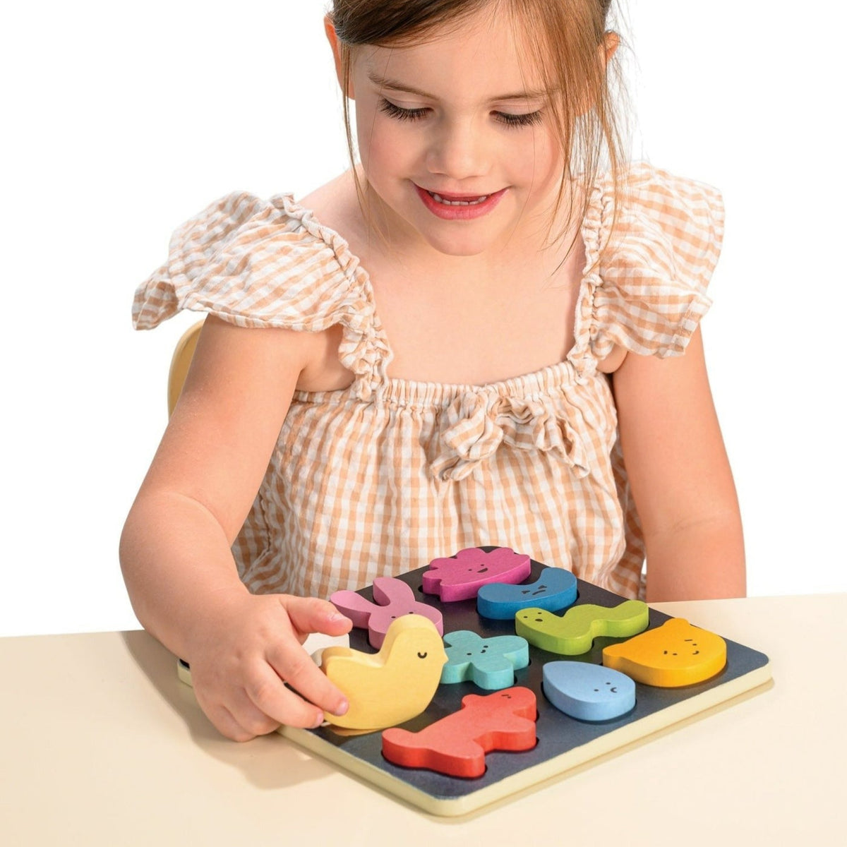 Child playing with a colorful wooden puzzle on a white background