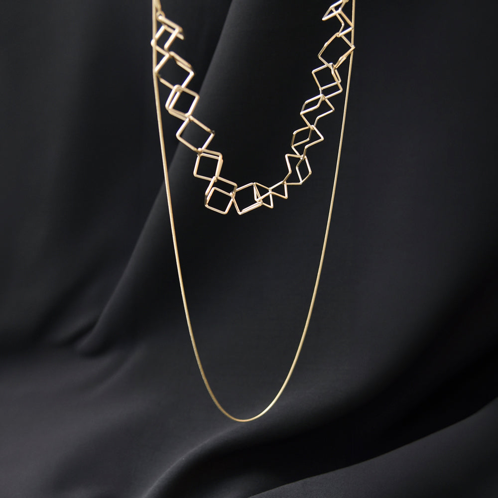 Styled view of looped gold necklace on black fabric.