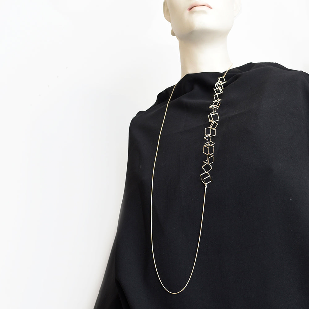 Styled view of long silver necklace on black fabric.
