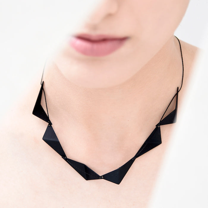 Image of geometric short necklace on model.