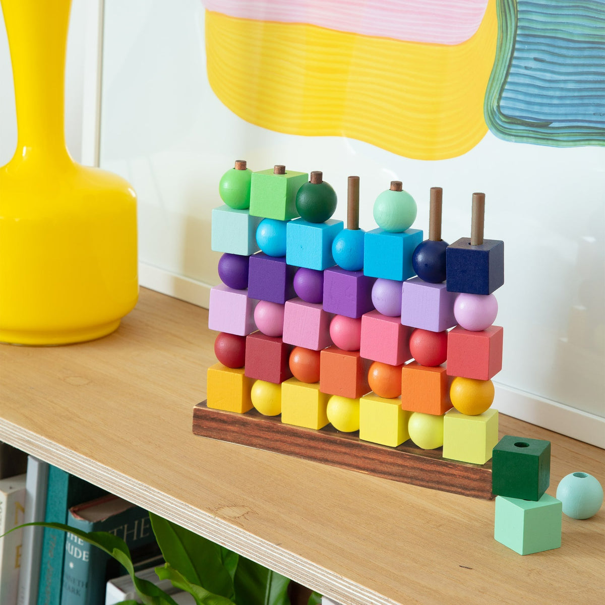 Colorful geometric toy on a wooden shelf with decorative items in the background