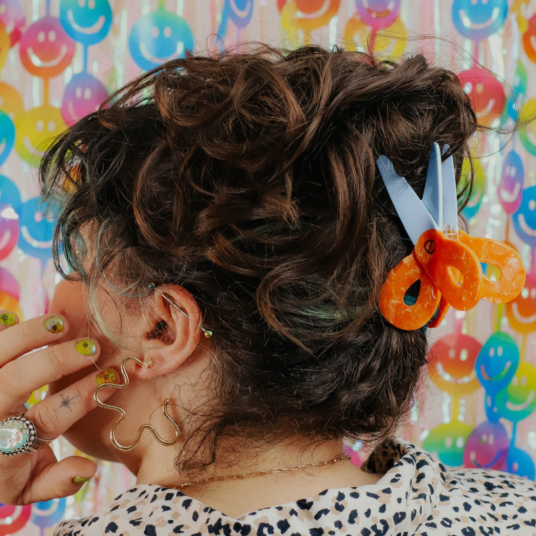 Person with styled hair featuring a colorful hair clip against a multicolored background