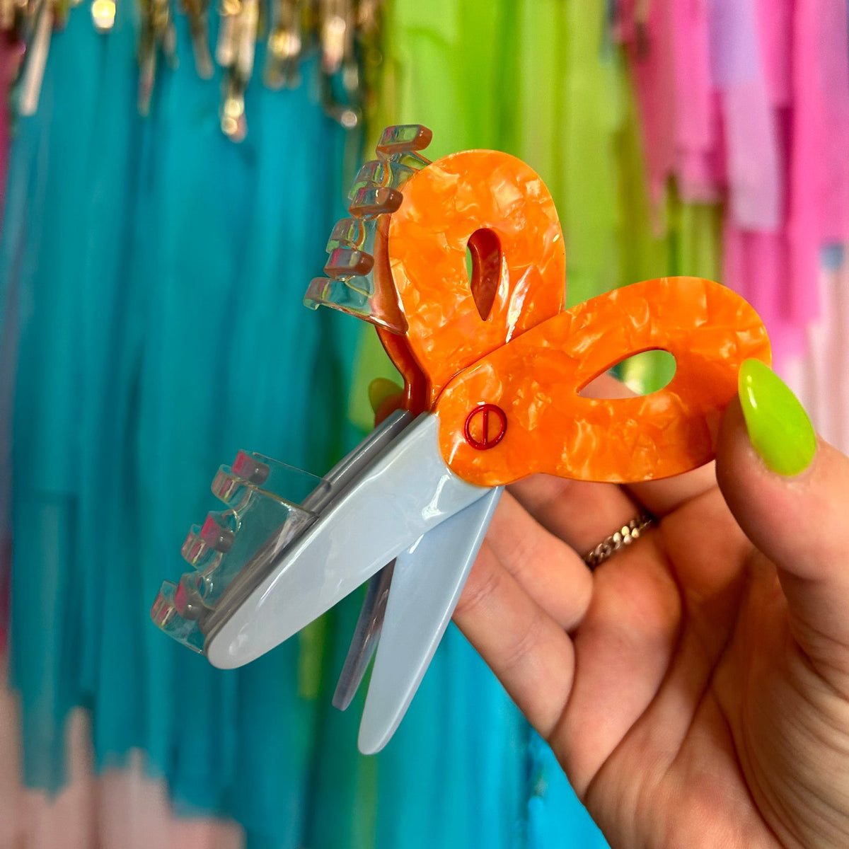 Hand holding scissors hair claw with colorful background