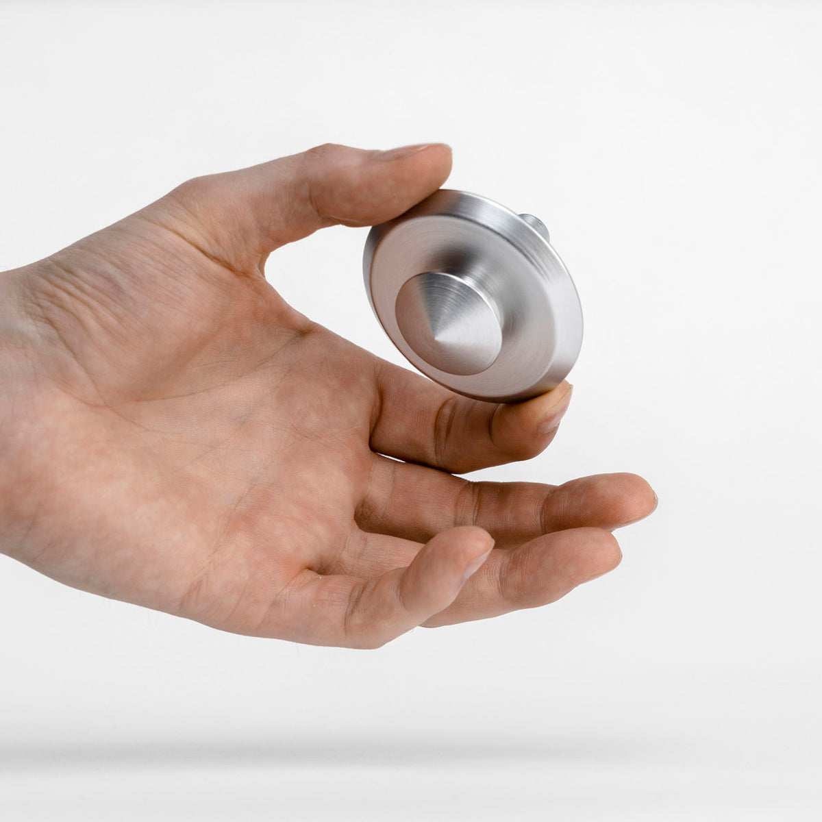 Hand holding a metallic object against a white background
