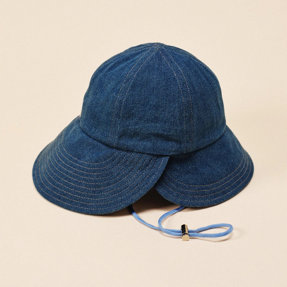 Blue denim bucket hat with a strap on a beige background