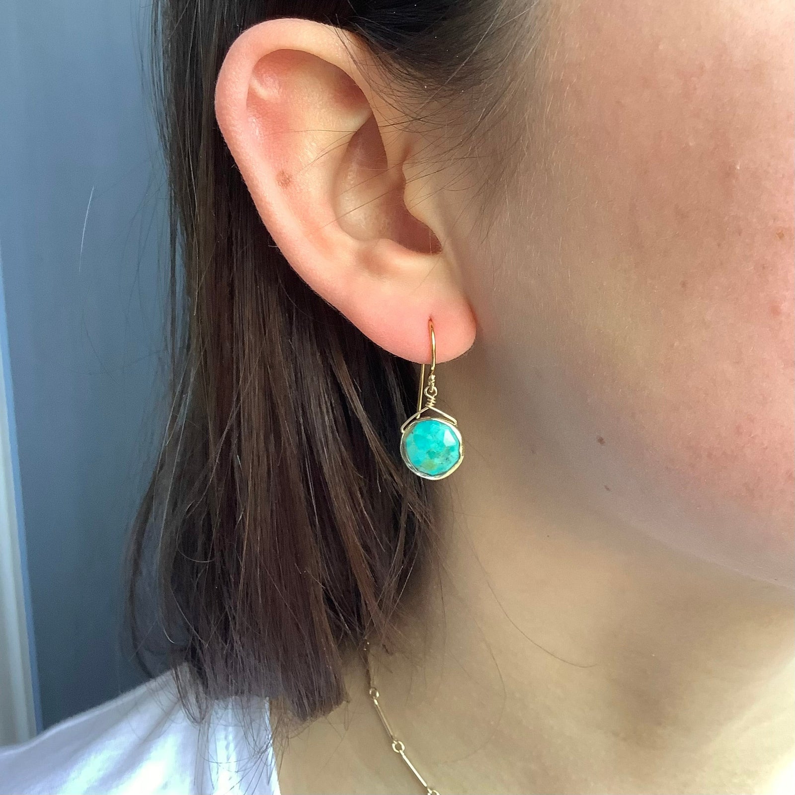 Turquoise stone earrings with silver wire wrapping on a white background