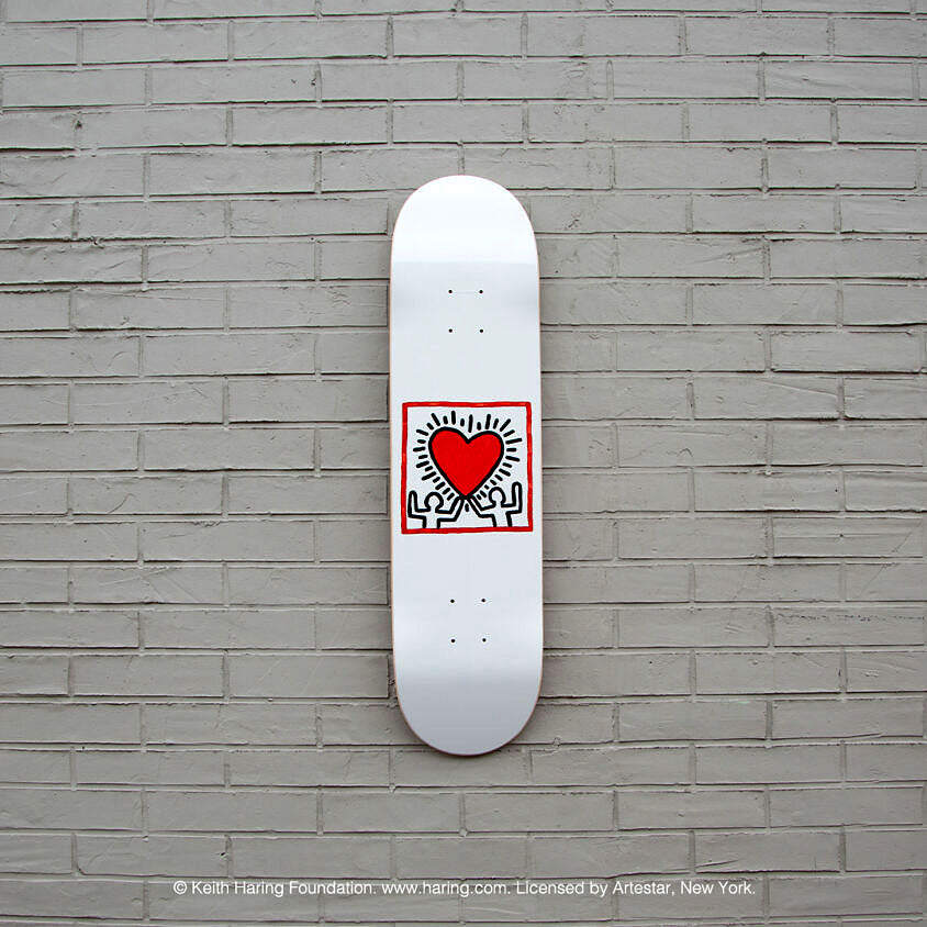 The Keith Haring Heart Skateboard on a brick wall.