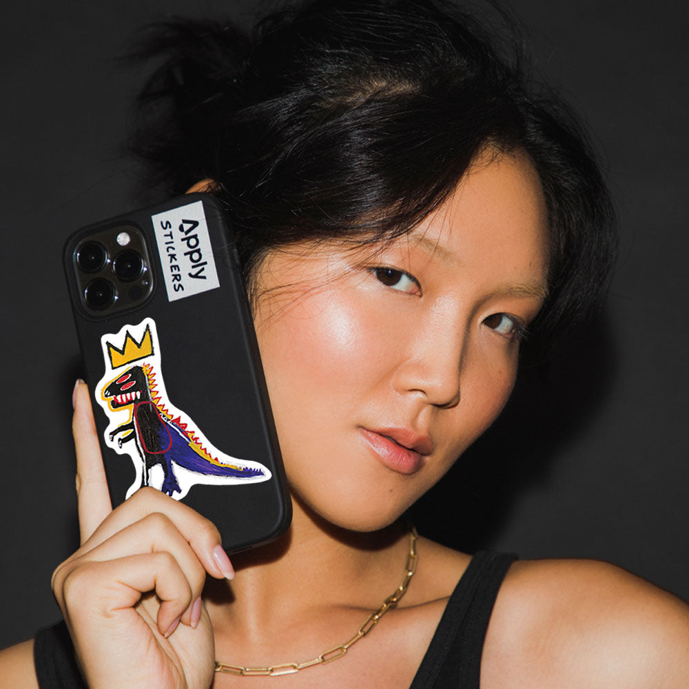 Model holding phone with Basquiat Dino Pez Dispenser Sticker by Apply Stickers.