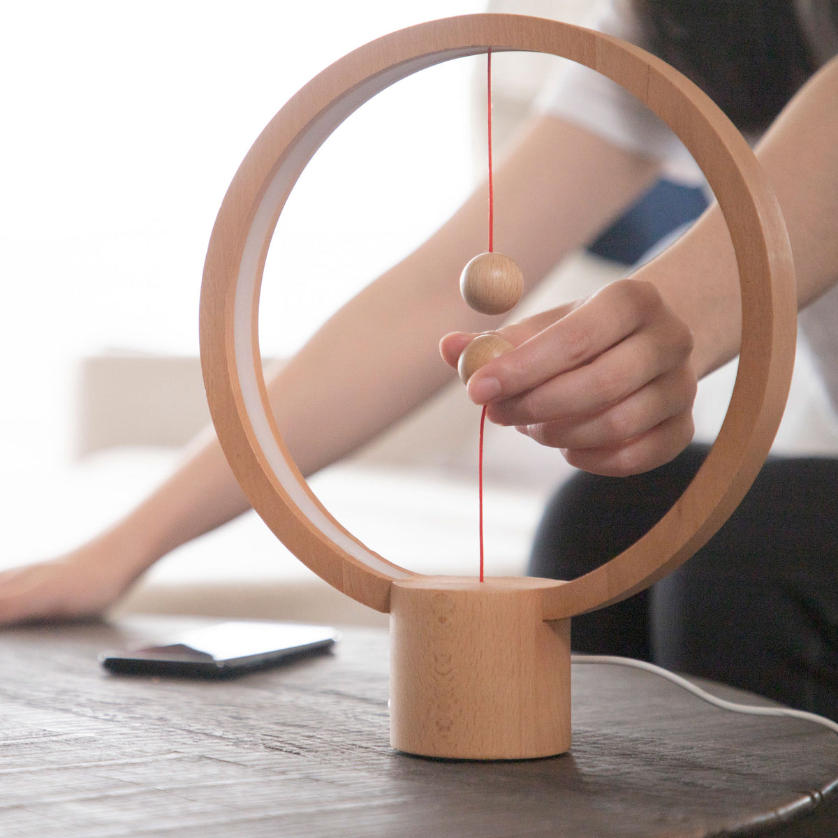 A hand turns on the Heng Round Light Wood.