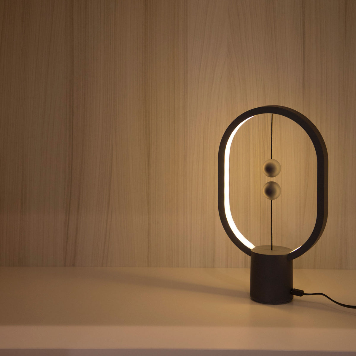 A lit Mini Heng Balance Lamp in a room&#39;s corner.