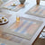Mesa Opal placemat, soft blue and white stripes horizontal, with smaller orange vertical stripes. Two white triangles overlay.