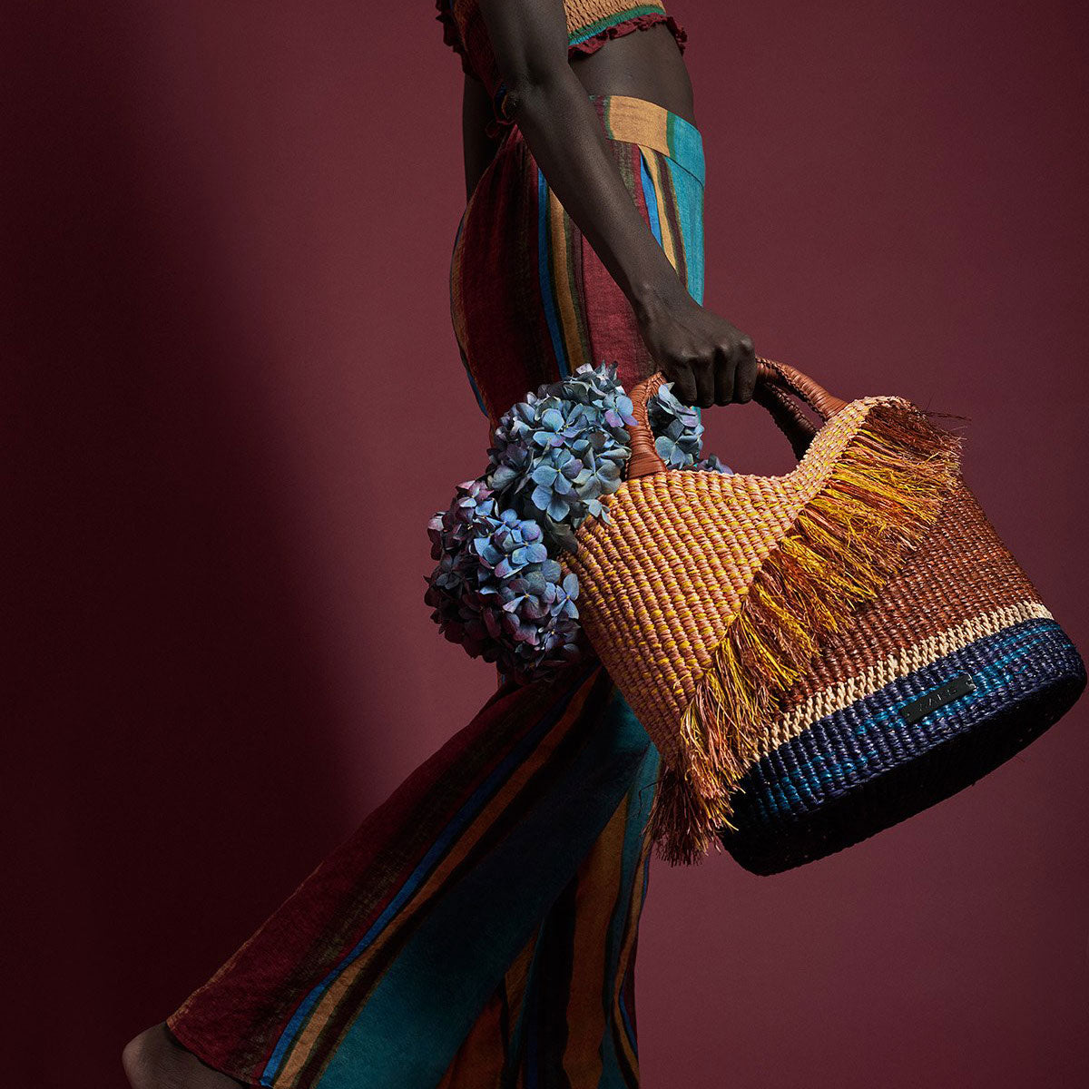 A model holds the Oroo Oak Bag with flowers inside.