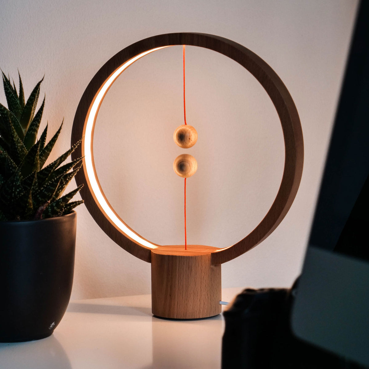 The Heng Round Light Wood lighting a table.