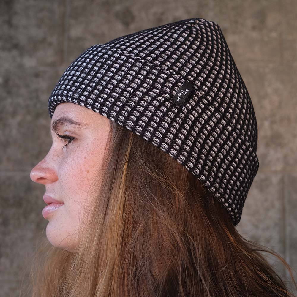 Model Wearing SFMOMA Rib Hat: Black + Grey in front of concrete background.