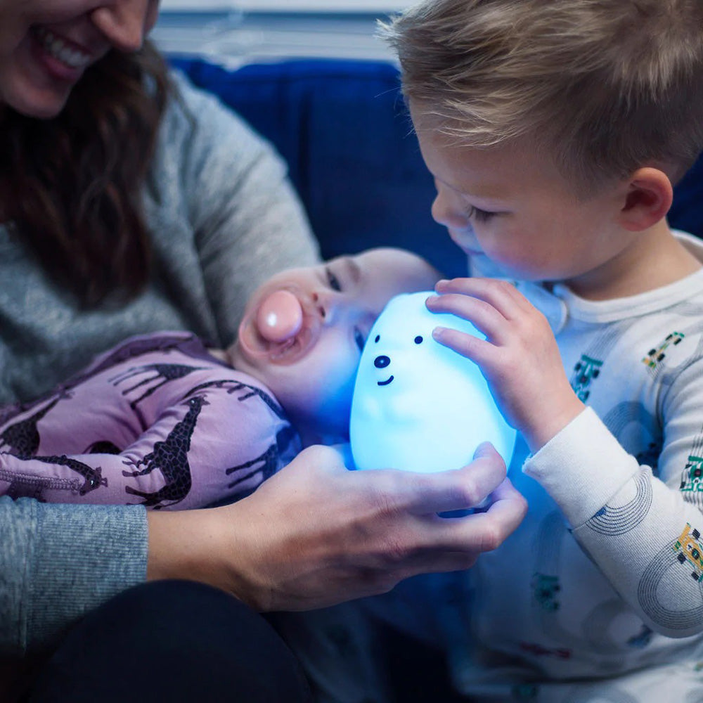 Kid holding lighted bear with mother and baby.