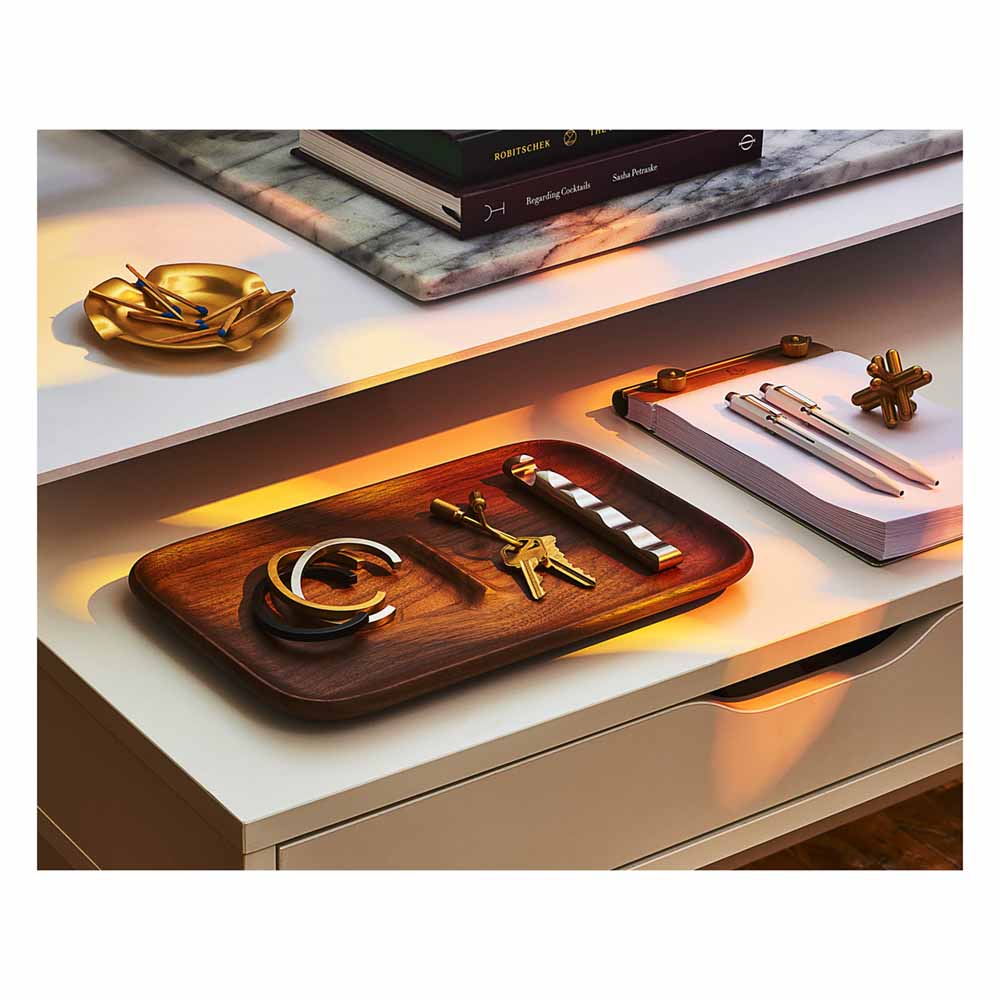 A Closed Helix Keyring: Brass in a tray with other accessories on a shelf.