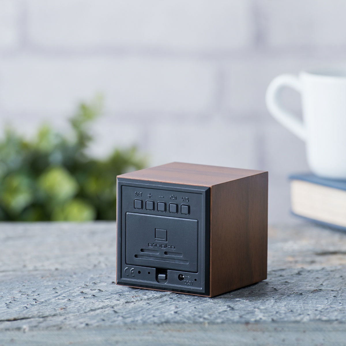 The back of the Cube Click Clock: Walnut displayed on a table outdoors.