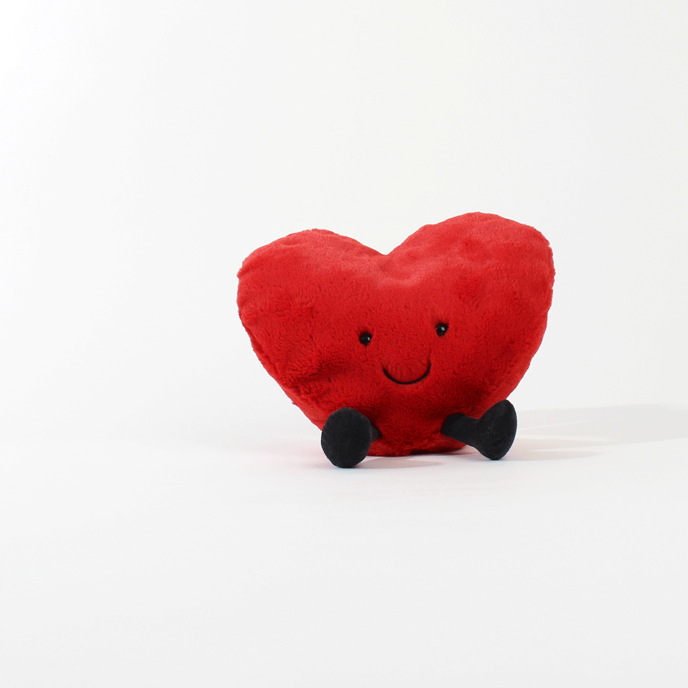 Small Amuseable Red Heart sitting with legs out on white background.