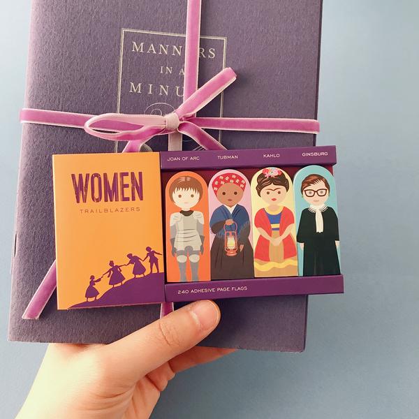 A hand holding the Women Trailblazer Sticky Notes packaged with a notebook.