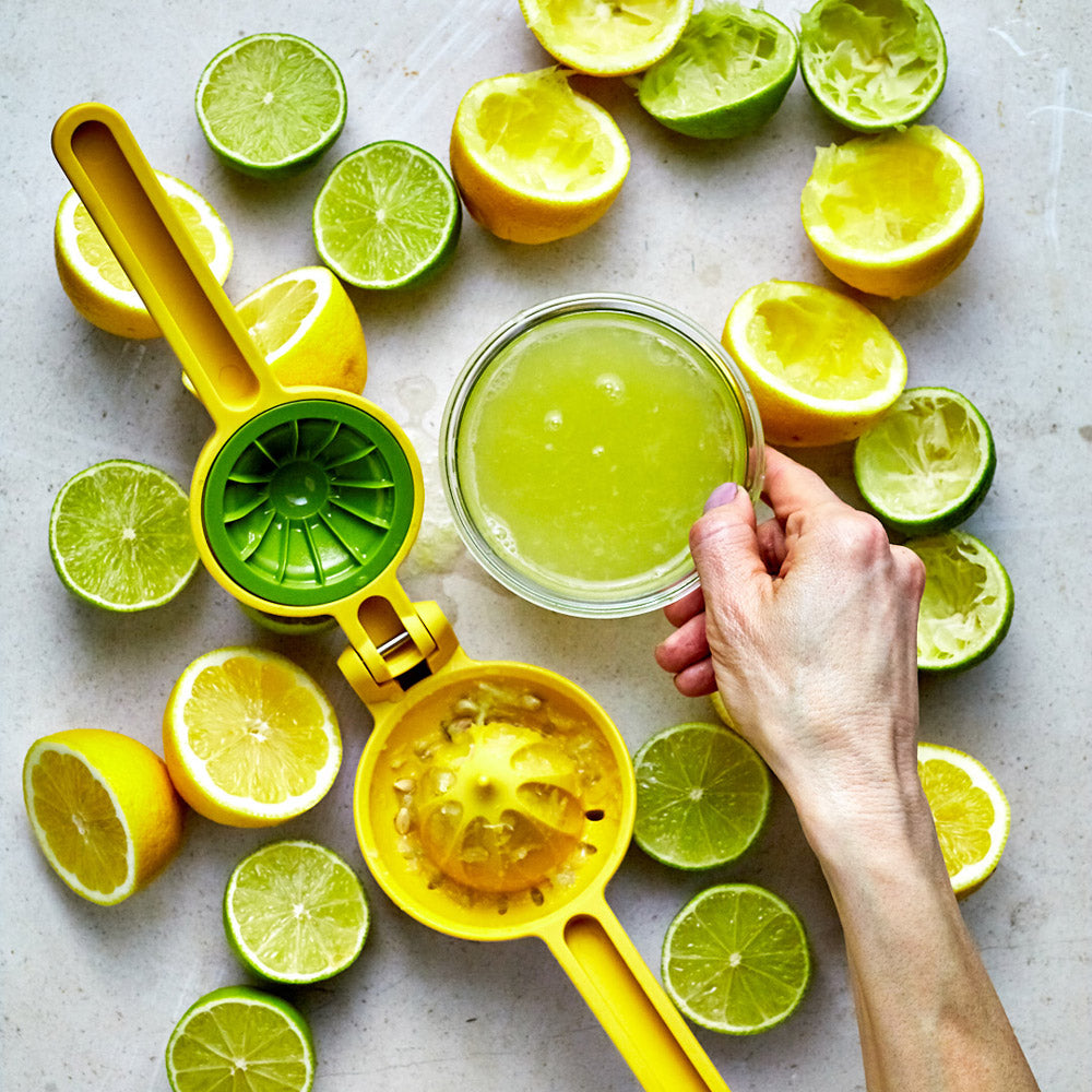 Lifestyle photo of opened citrus press with model holding cup of lemon juice.