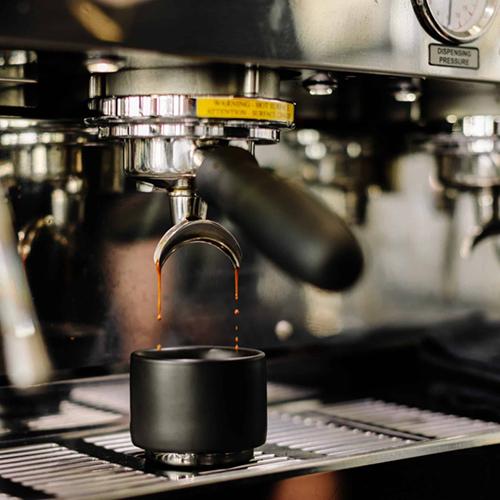 One of the black Monty Espresso cups in an espresso machine.