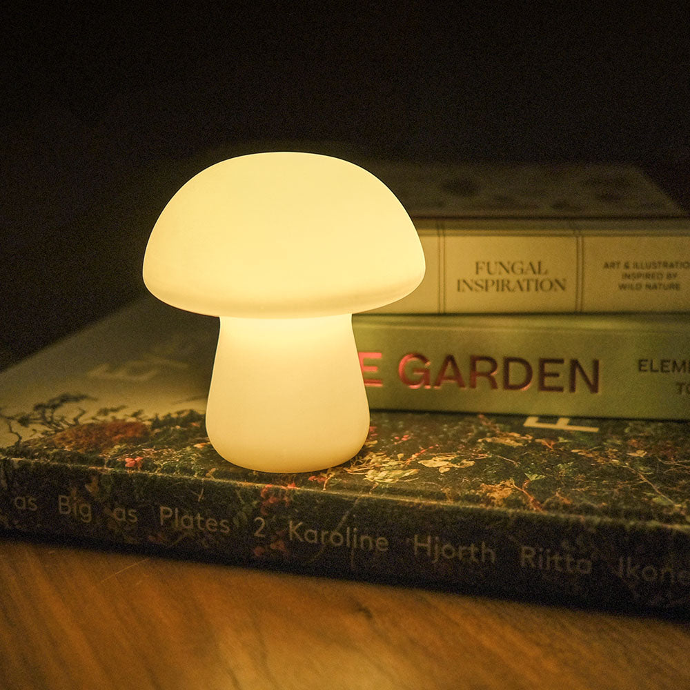 Medium Mushroom Light by Kikkerland, turned on, on stack of books.