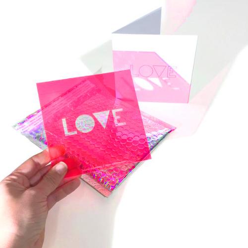 The Neon Greetings Love displayed with included bubble mailer and white card.