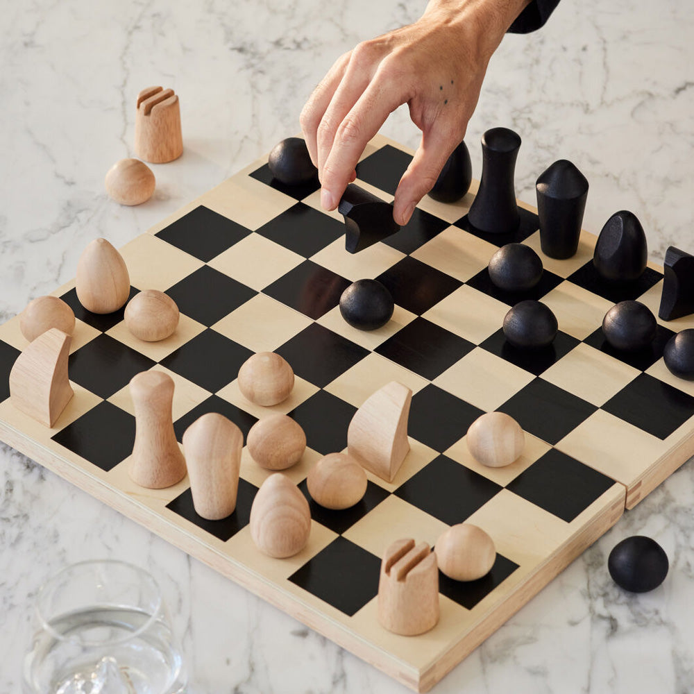Hand moving chess piece on chess set.