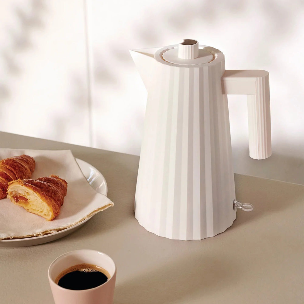 Lifestyle photo of kettle with coffee and croissant.