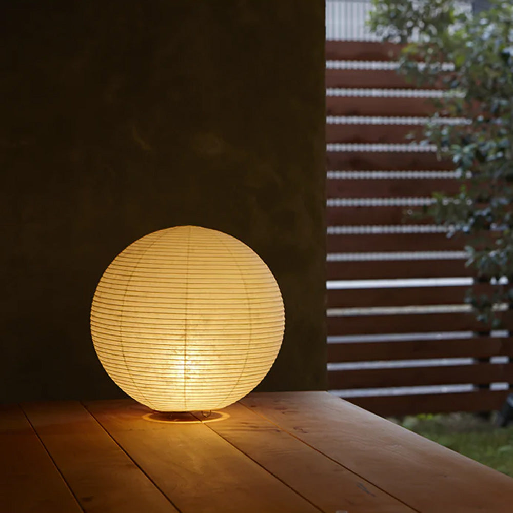 Photo of ASANO&#39;s &#39;Globe Paper Moon&#39; washi paper lamp shade illuminated on a wooden outdoor deck.
