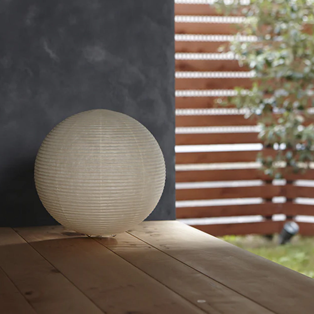 Photo of ASANO&#39;s &#39;Globe Paper Moon&#39; washi paper lamp shade on a wooden outdoor deck.