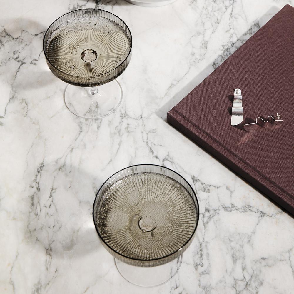 The Ripple Champagne Smoke Glasses: Set of 2 displayed on a marble surface.