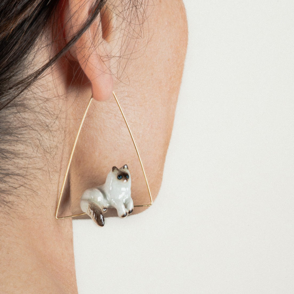 Model wearing Siamese Cat Triangle Earrings by Nach in front of white background.