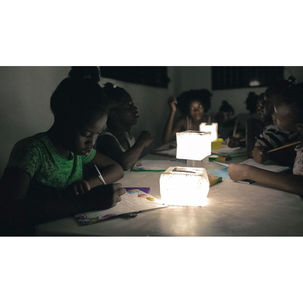 Several SolarPuffs lighting a table with children writing.