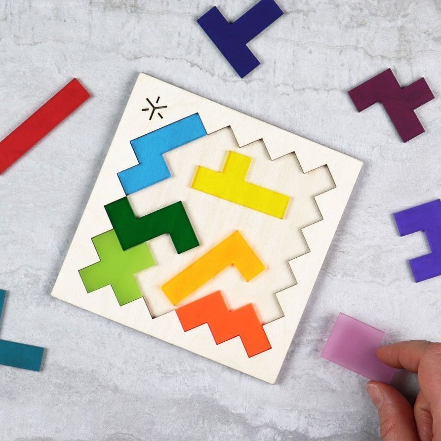 A hand assembling a Square Pentomino Puzzle: Rainbow.