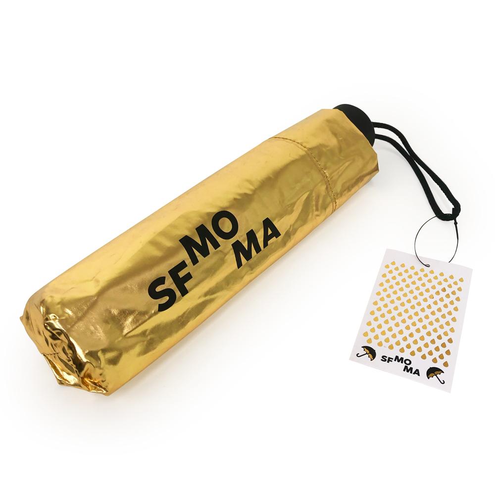 A SFMOMA Black and Gold Umbrella in its gold sleeve. 